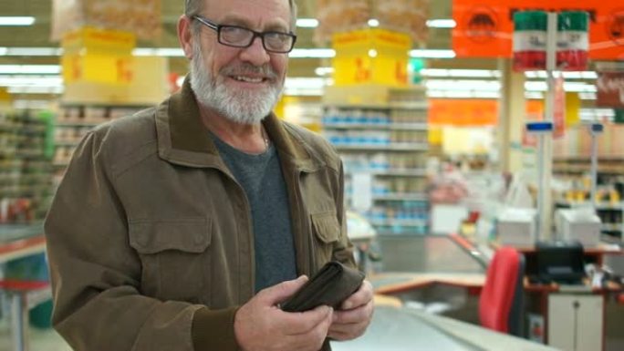 超市里一位老人手里拿着钱包的亲密肖像。养老金领取者微笑