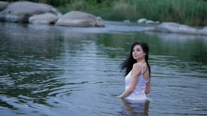 美丽的黑发女孩，长发站在水中。慢动作。