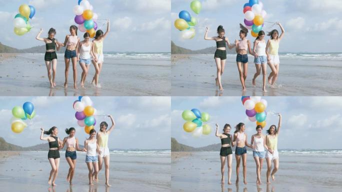 一群朋友拿着五颜六色的气球在沙滩上散步很开心。