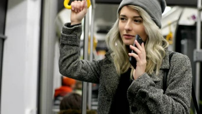 有人打电话来。微笑的年轻女子戴着耳机在公共交通工具中接听来电
