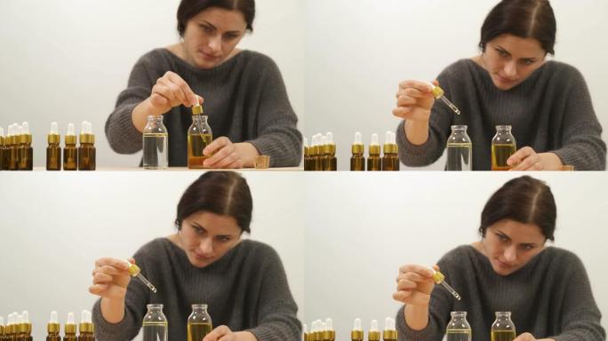 女人用第一瓶的油装满移液器的特写镜头。完整的移液器固定在第二个瓶子上方，水和油滴滴入水中，形成两层