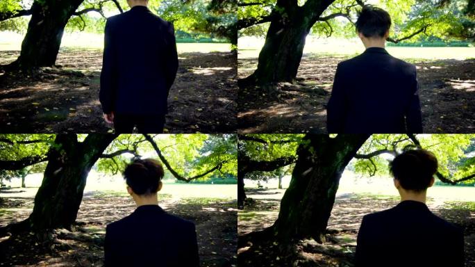 电影慢镜头-年轻的亚洲探员西装男子走向公园的大树