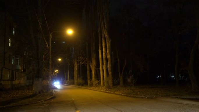 在深秋的夜晚，汽车沿着带有路灯的城市街道行驶
