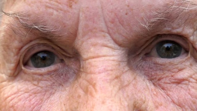 祖母带着悲伤的景象看着镜头的肖像。闭上老年妇女的灰色眼睛，周围有皱纹。高级女士的悲伤表情。