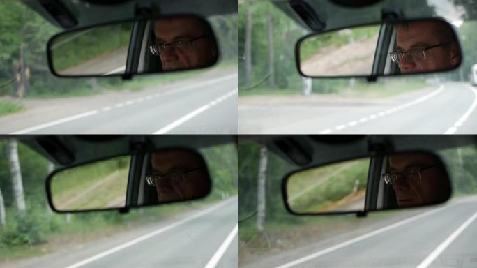 高级男子在乡间小路开车。汽车后视镜中面部的反射。特写