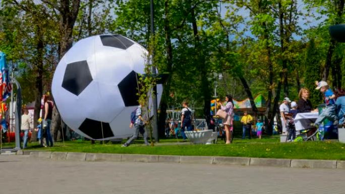 人们在城市公园的节日。时间流逝。一群游客在夏日靠近一个大足球。延时。