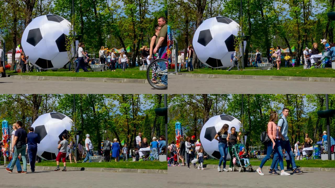 人们在城市公园的节日。时间流逝。一群游客在夏日靠近一个大足球。延时。