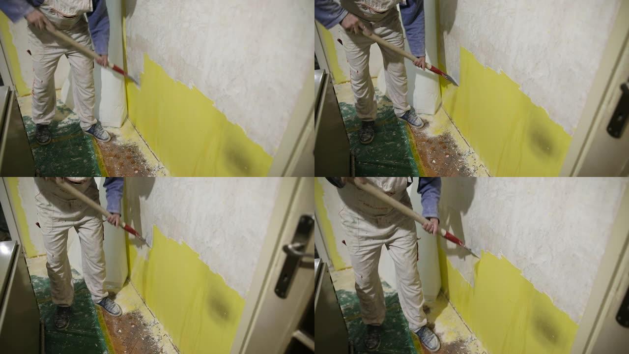 家庭装修，工人用刮刀从混凝土墙上清除旧的黄色油漆