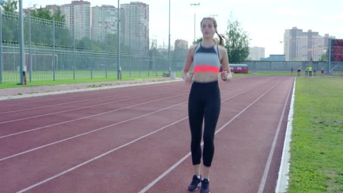 短跑练习前，运动女孩在跑道上做高膝盖运动热身的全程镜头