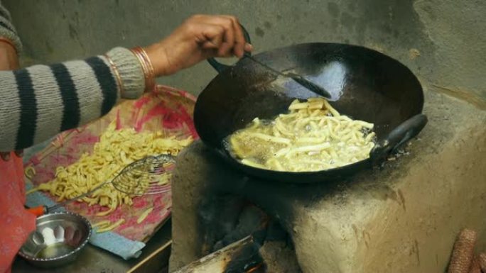 印度妇女在土坯炉子上烹饪传统小吃。