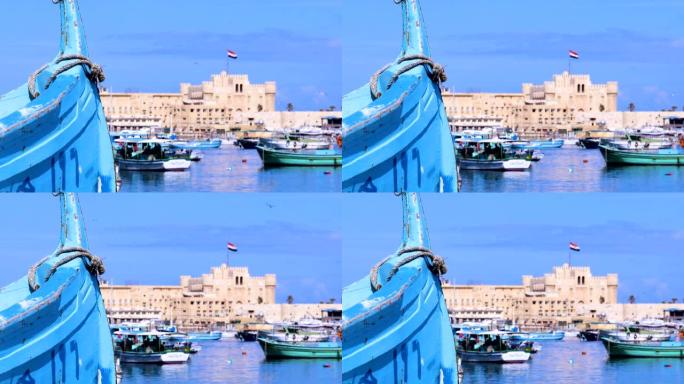 从埃及亚历山大港的地中海俯瞰凯特湾城堡。蓝蓝的天空下，城堡前有很多渔船。