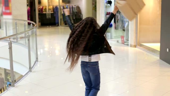 快乐的小女孩在购物中心散步时为新的购物感到高兴。