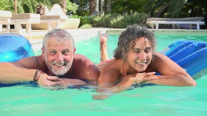 祖父母和孙子在游泳池的充气床上