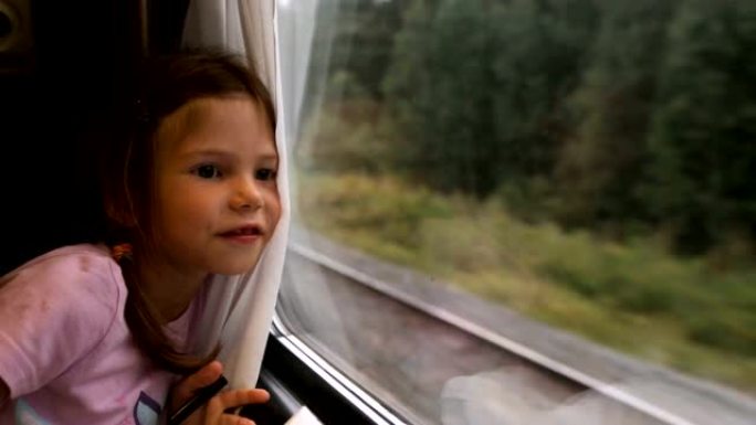 小女孩在火车上透过窗户看