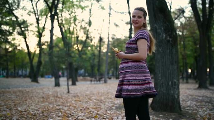 秋天在公园里快乐的孕妇。