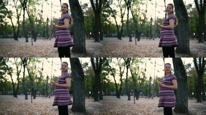秋天在公园里快乐的孕妇。
