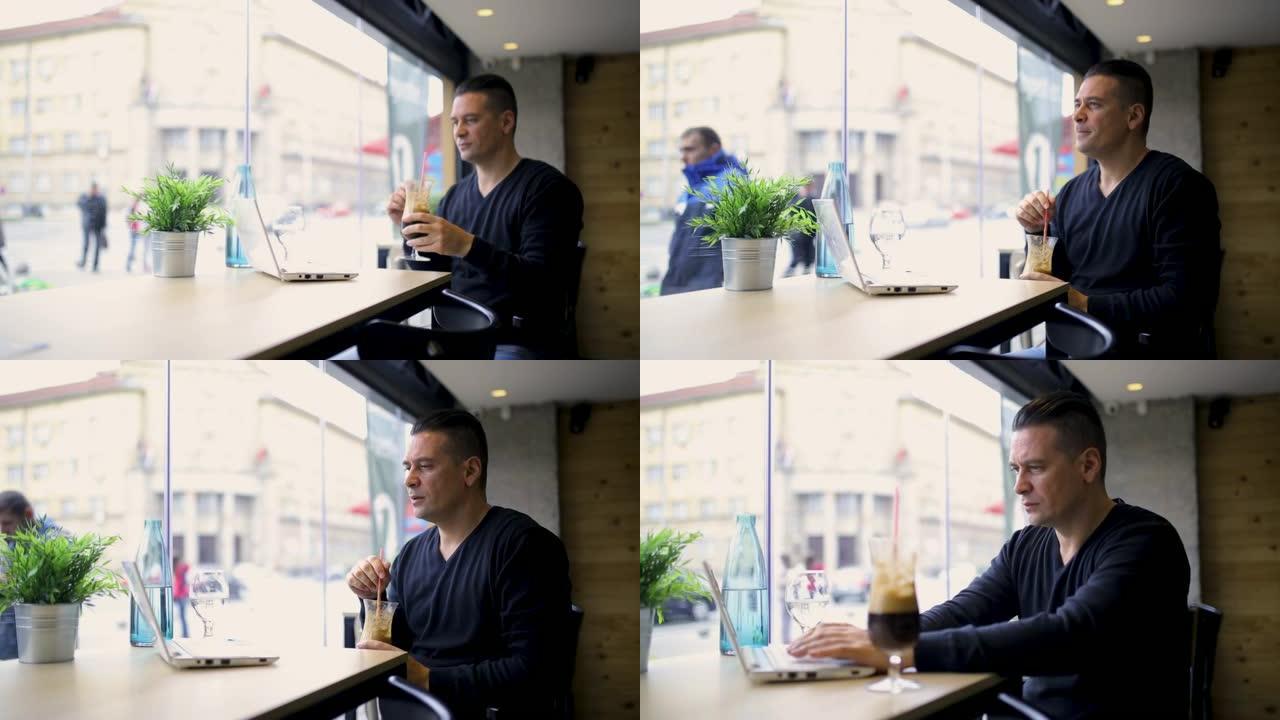 男人在咖啡吧里用笔记本电脑喝咖啡