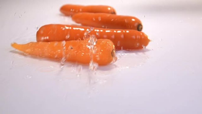 胡萝卜落在白色背景的白色桌子上的水中。慢动作240 fps