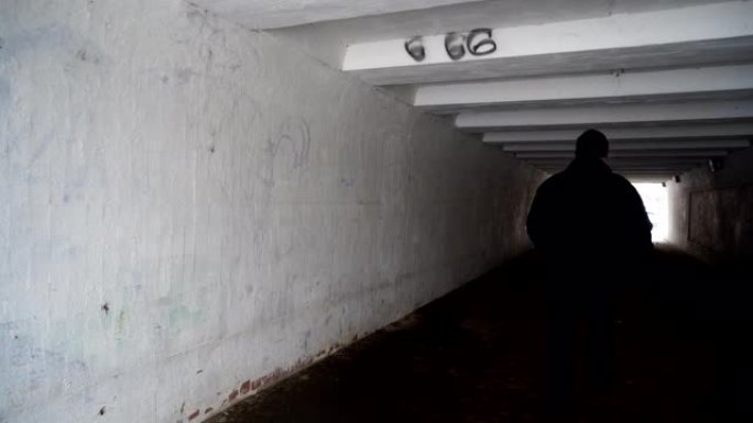 男子走过黑暗的行人地下过街隧道