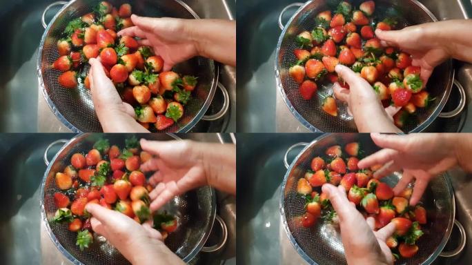 红色，成熟的草莓在水槽中洗净，水溅满了闪亮的水滴，看起来非常新鲜和干净