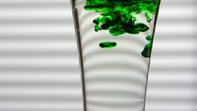 绿色染料溶解在白色背景上的玻璃水中