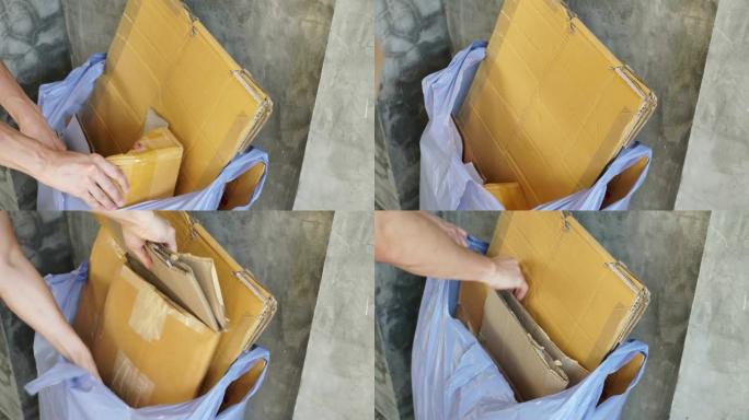 手工将废弃的棕色瓦楞纸纸箱收集到垃圾袋中进行回收处理