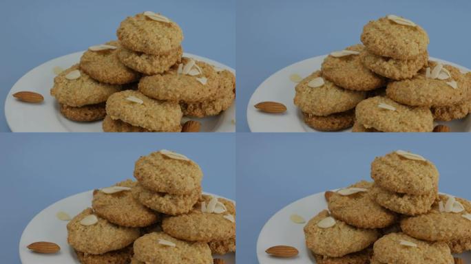 无麸质饼干杏仁，杏仁片，白色盘子，设置在浅蓝色背景上。