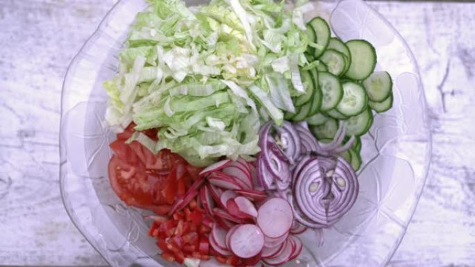 新鲜切碎的夏季沙拉。玻璃沙拉碗中的许多美味蔬菜-黄瓜，生菜，萝卜，西红柿，红洋葱