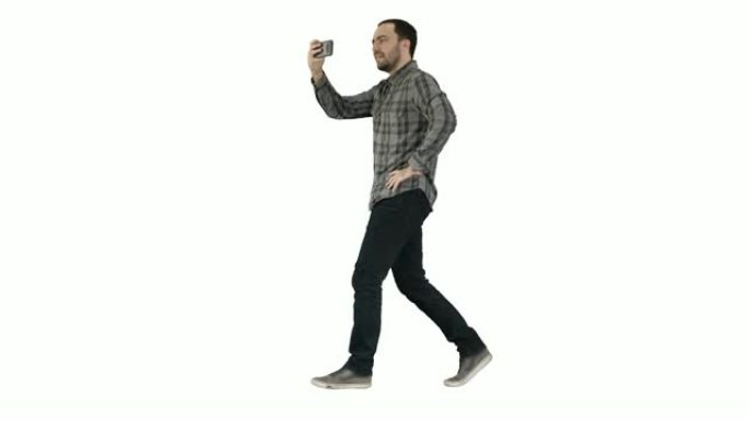 年轻人在白色背景上行走时用智能手机拍照