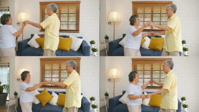 亚洲老年夫妇喜欢在家客厅跳舞。在家老化的概念。