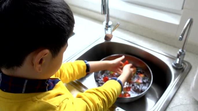 亚洲男孩在家里洗草莓