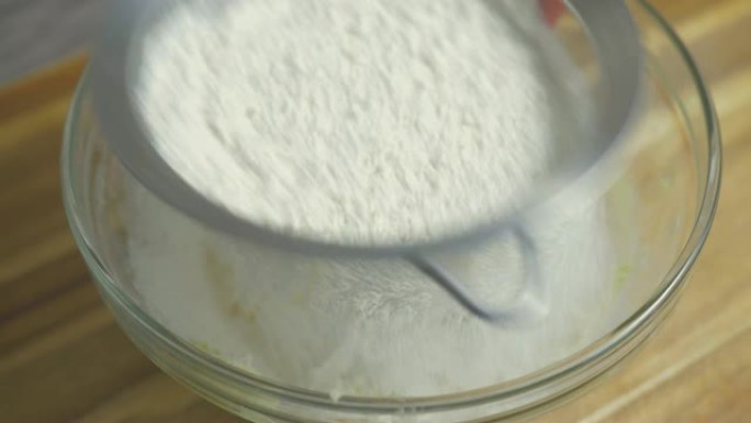 将面粉筛入黄油和糖的搅拌碗的特写视图
