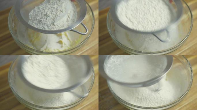 将面粉筛入黄油和糖的搅拌碗的特写视图