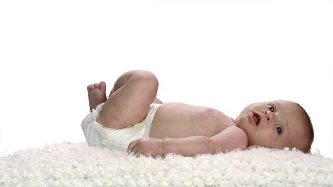 一个婴儿躺在柔软的白色毛茸茸的床单上