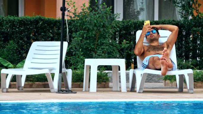 男子在游泳池旁的椅子上晒日光浴