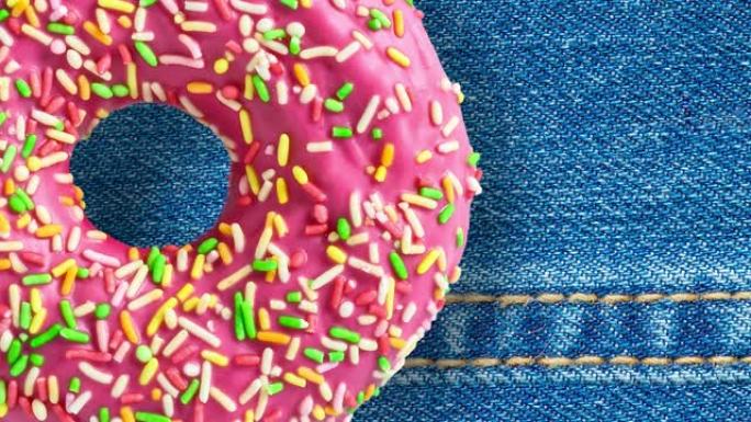 粉色甜甜圈在蓝色牛仔裤背景上旋转