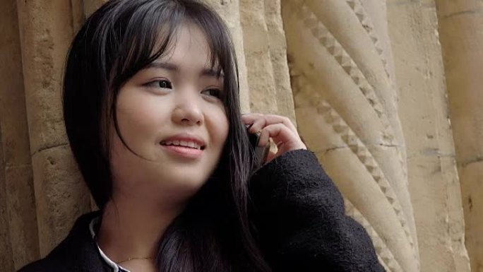 微笑的年轻亚洲妇女使用手机: 手机对话