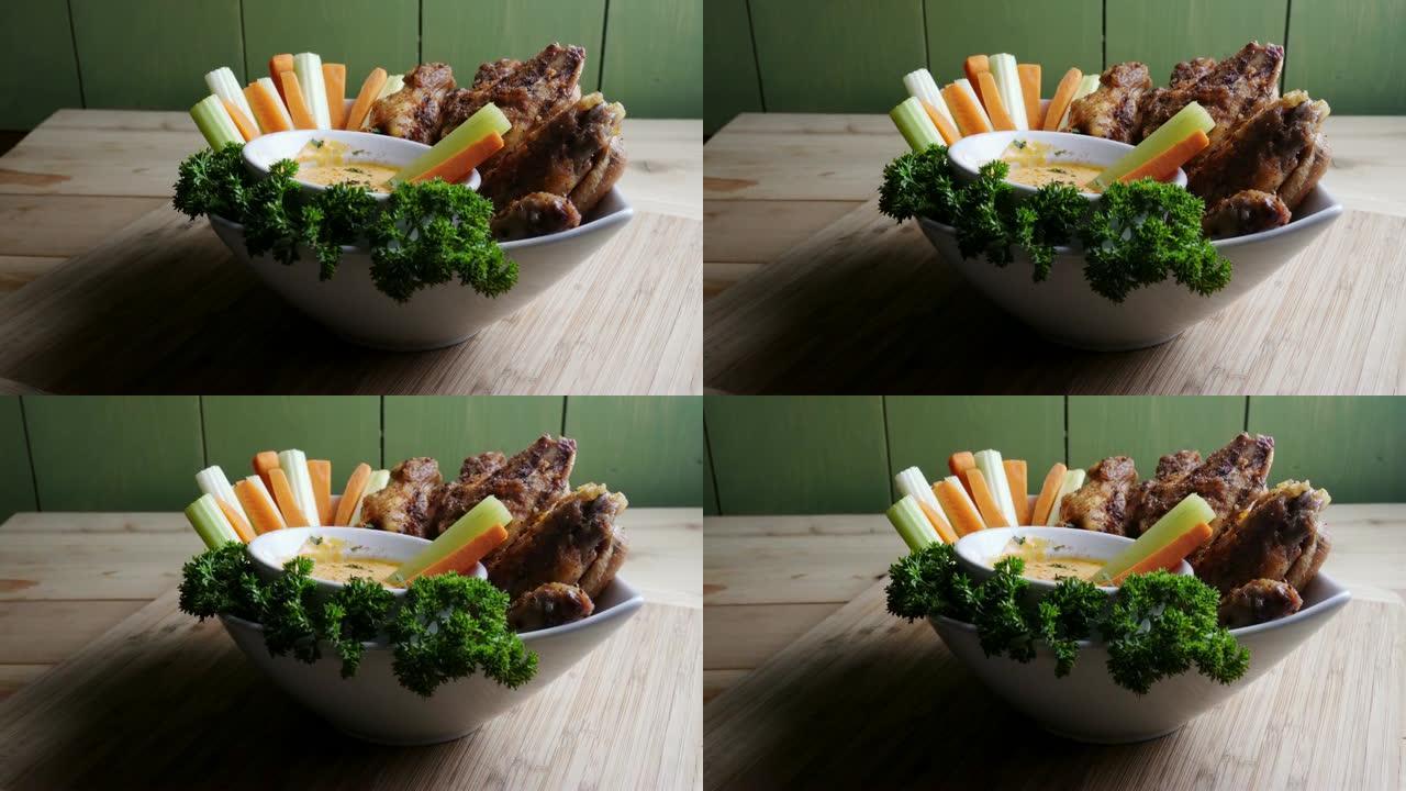 一碗健康烘烤的烤鸡翅，配以辣酱芹菜和胡萝卜条