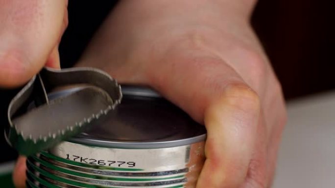 用手动开罐器打开一罐食物并取下盖子顶部的手。