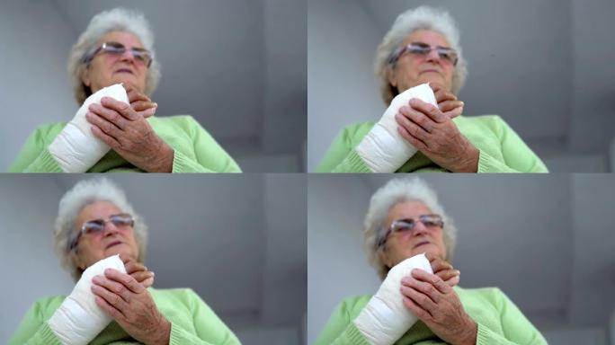 老妇人按摩她受伤的断手坐着，电影的dop