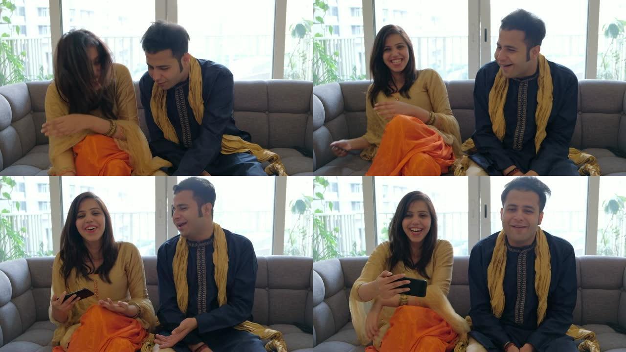 夫妻俩在电话视频会议上交谈时分享笑声和微笑，并穿着传统的印度服装与相机外的人交谈
