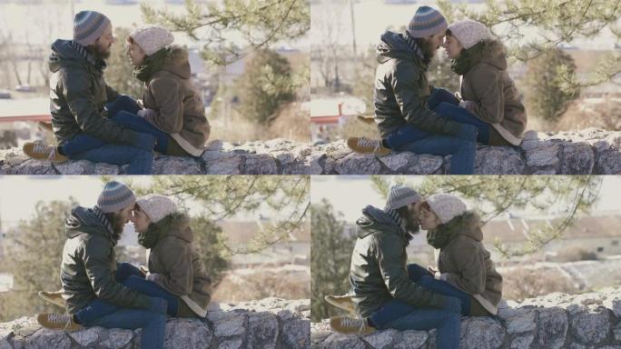 恋爱中的年轻夫妇坐在石墙上
