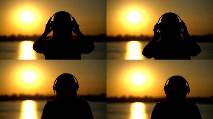 女人在日落背景上戴着耳机听音乐