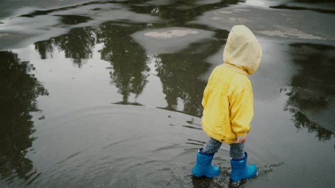 小男孩在户外散步，在水坑上跳跃