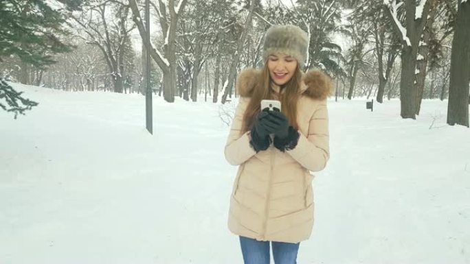 冬季公园4k使用智能手机的女人