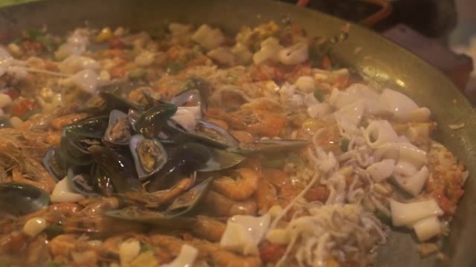 西班牙海鲜饭在锅里烹饪特写。加工准备传统西班牙海鲜饭与海鲜在餐厅的热痛。食物烹饪概念。民族美食