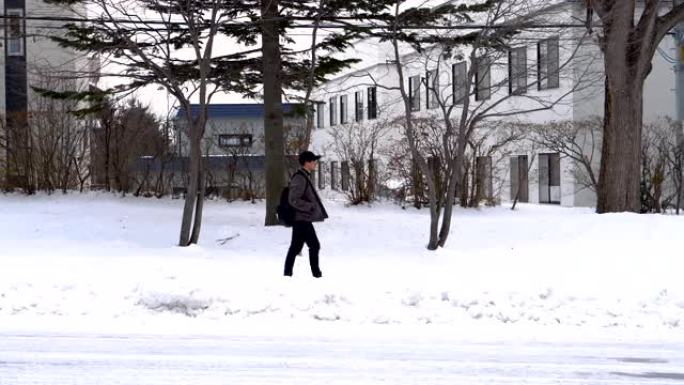 侧视图-冬天在郊区的白雪覆盖的人行道上行走的人