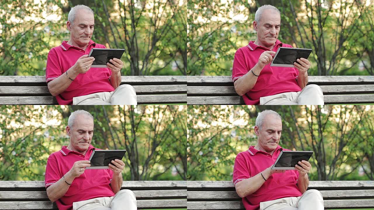 退休的老人在公园的餐桌上休息和使用平板电脑