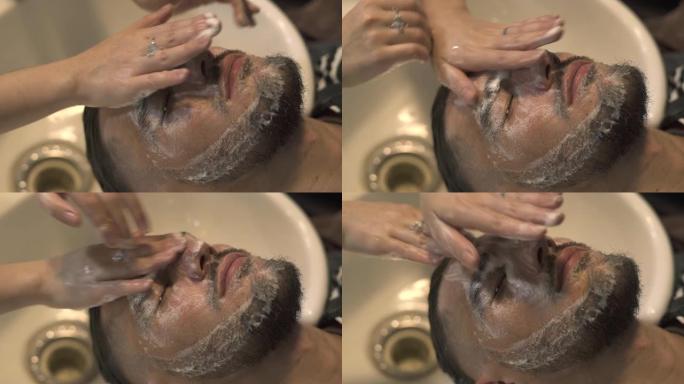 年轻男子在男性沙龙洗脸按摩。近距离面部按摩的胡子男子在理发店。男性护肤理念