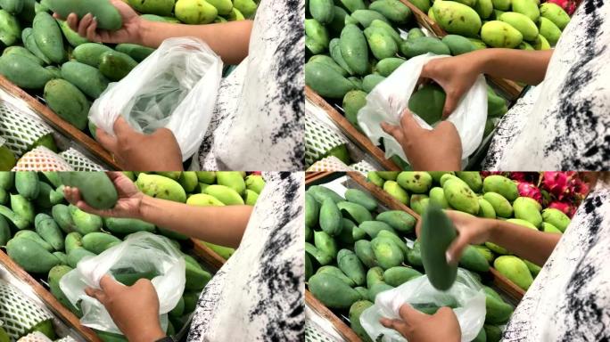 女人的手在超市购买新鲜有机食品，芒果